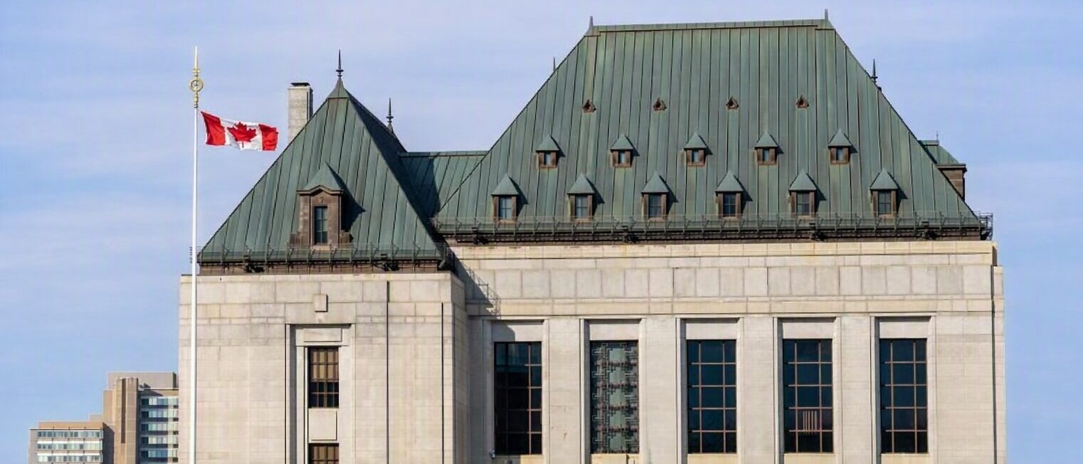 Supreme Court of Canada building in Ottawa centered with the Canadian flag flying, framed by sky‑tone buffer space above and below